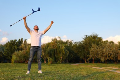 Man raising elbow crutch up to sky on sunny day, space for text. Healing miracle