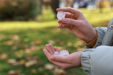 Woman holding hail grains after thunderstorm in park, closeup