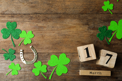 Flat lay composition with clover leaves and block calendar on wooden background, space for text. St. Patrick's day
