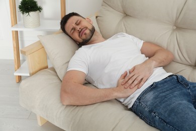 Man suffering from pain in lower right abdomen on sofa at home. Acute appendicitis