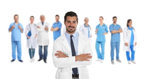 Handsome young doctor and blurred view of medical staff on white background. Banner design
