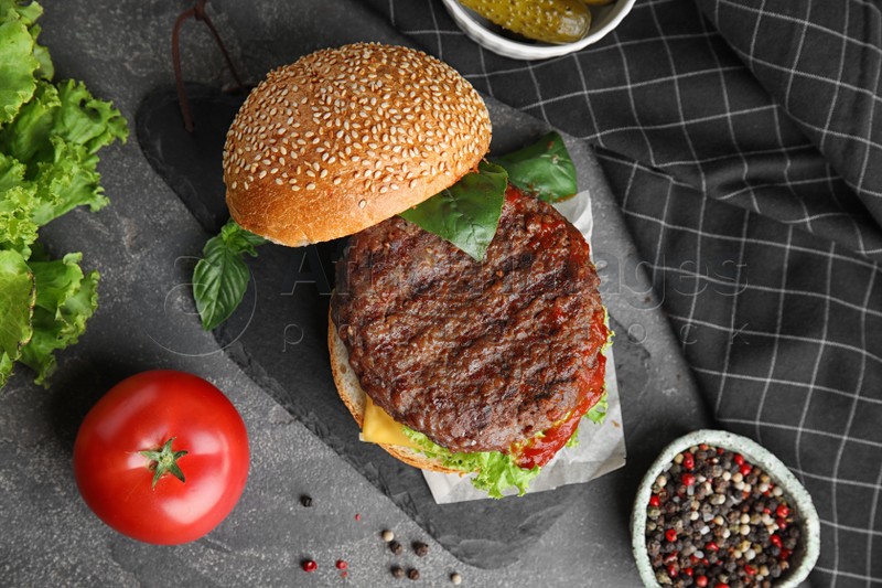 Delicious burger with meat cutlet on grey table, flat lay