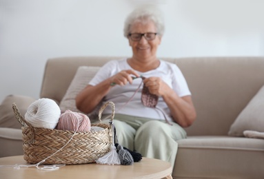 Elderly woman crocheting at home. Creative hobby