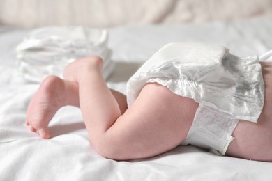 Photo of Little baby in diaper lying on bed, closeup