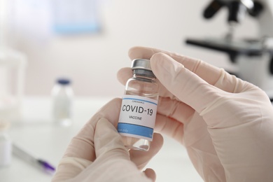 Doctor holding vial with vaccine against Covid-19 indoors, closeup