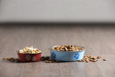 Bowls with dry dog food on wooden floor indoors