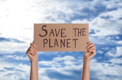 Protestor holding placard with text Save The Planet against blue sky, closeup. Climate strike