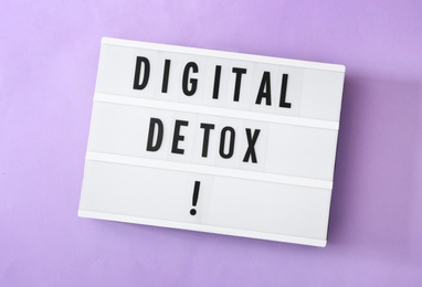 Photo of Lightbox with words DIGITAL DETOX on violet background, top view