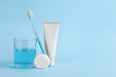 Mouthwash, toothbrush, paste and dental floss on light blue background, space for text