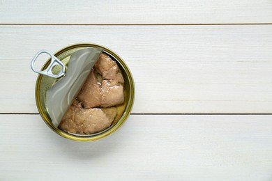 Photo of Open tin can of tasty cod liver on white wooden table, top view. Space for text