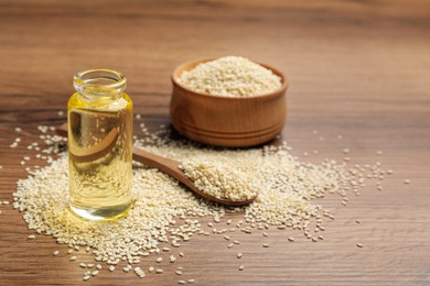 Bottle of sesame oil and seeds on wooden table. Space for text