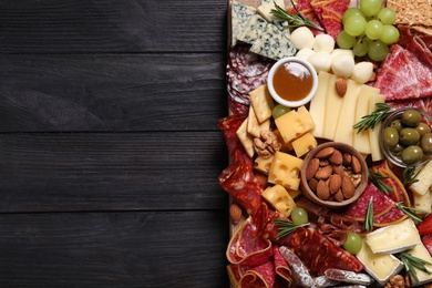 Assorted appetizers served on black wooden table, top view. Space for text