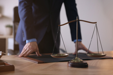 Male lawyer at table in office, focus on scales of justice