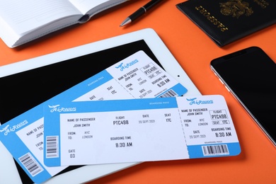 Composition with avia tickets and tablet on orange background. Travel agency concept