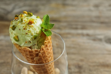 Delicious green ice cream served on wooden table, closeup. Space for text