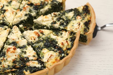 Photo of Taking piece of delicious homemade spinach quiche on white wooden table, closeup