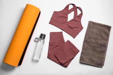 Yoga mat, stylish sportswear and bottle of water on white background, flat lay