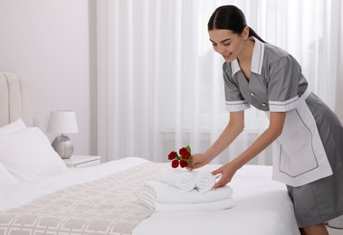 Chambermaid putting flowers with fresh towels in hotel room. Space for text