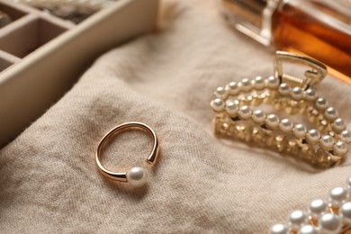 Elegant hair clip and ring with pearls on beige fabric, closeup