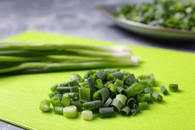Photo of Chopped green spring onion and stems on grey marble table, closeup