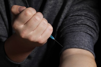 Photo of Addicted man with syringe taking drugs, closeup