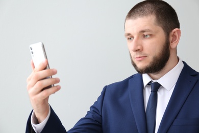 Man unlocking smartphone with facial scanner on light background. Biometric verification