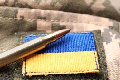 Bullet and Ukrainian army patch on military camouflage, closeup