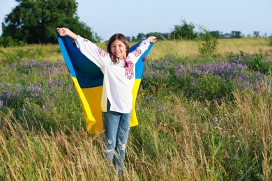 Happy girl with national flag of Ukraine in field. Space for text