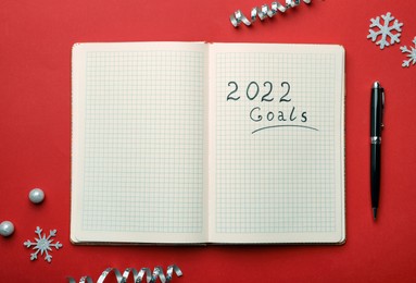 Photo of Open planner and Christmas decor on red background, flat lay. Planning for 2022 New Year