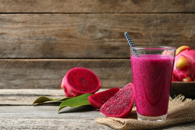 Glass of tasty pitahaya smoothie and fresh fruits on wooden table, space for text