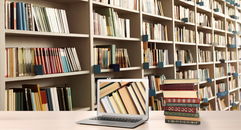 Digital library concept. Modern laptop on table and shelves with books indoors
