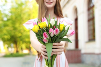 Teenage girl with bouquet of tulips on city street, closeup