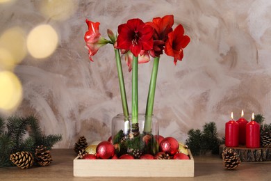 Photo of Beautiful red amaryllis flowers and Christmas decor on wooden table