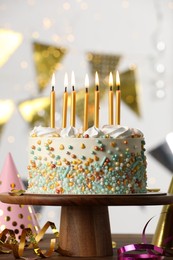 Beautiful birthday cake with burning candles and decor on wooden table