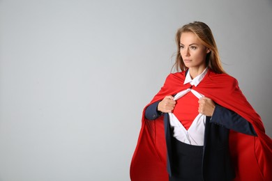 Confident businesswoman wearing superhero costume under suit on light grey background. Space for text