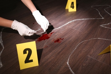 Detective taking blood sample from crime scene, closeup