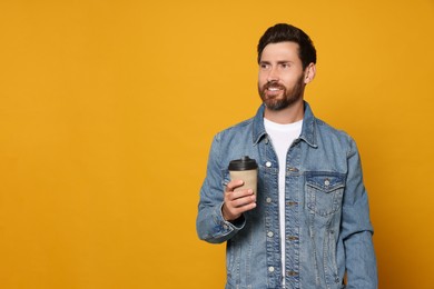 Photo of Bearded man with paper cup of drink on orange background. Space for text