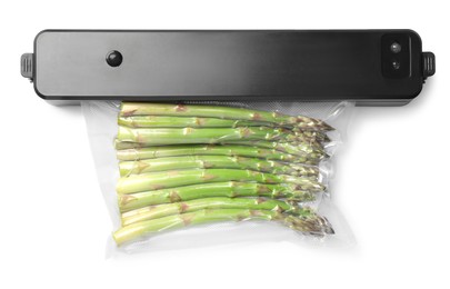 Sealer for vacuum packing with plastic bag of asparagus on white background, top view