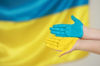 Little boy with painted hands near Ukrainian flag, closeup and space for text. Love Ukraine concept