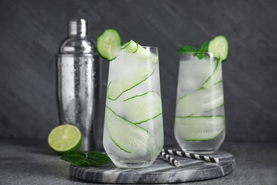 Photo of Glasses of refreshing cucumber water on dark grey table