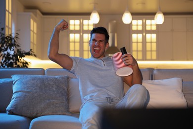 Man watching movie with popcorn on sofa at night