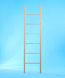 Photo of Modern wooden ladder on light blue background