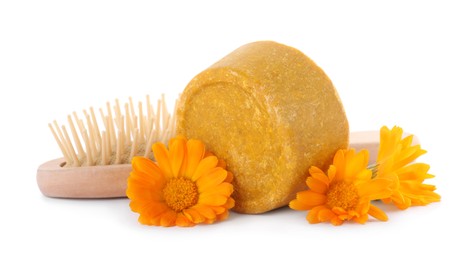 Yellow solid shampoo bar, hairbrush and flowers on white background. Hair care
