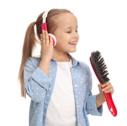 Photo of Cute little girl in headphones with brush singing on white background