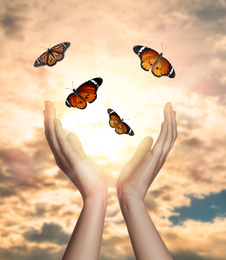 Woman releasing butterflies against beautiful sky outdoors, closeup. Freedom concept