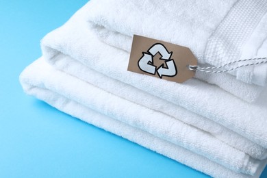 Stacked towels with recycling label on light blue background