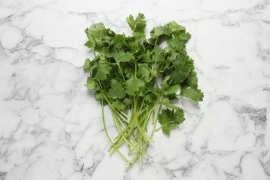 Bunch of fresh green cilantro on white marble table, top view