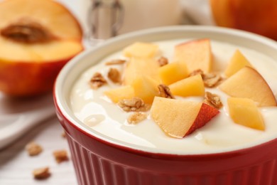 Delicious yogurt with fresh peach and granola in bowl on table, closeup
