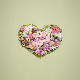Beautiful heart shaped floral composition on light green background, flat lay