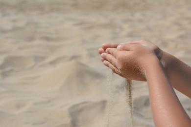 Child pouring sand from hands outdoors, closeup with space for text. Fleeting time concept